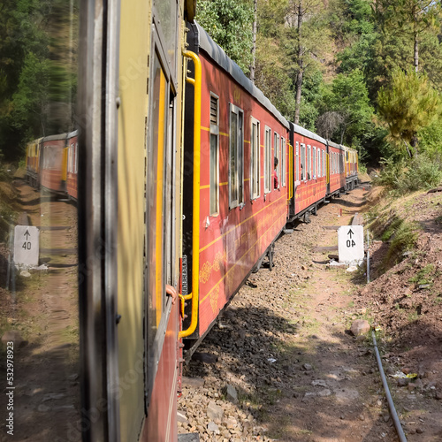 Toy Train moving on mountain slopes, beautiful view, one side mountain, one side valley moving on railway to the hill, among green natural forest. Toy train from Kalka to Shimla in India, Indian Train