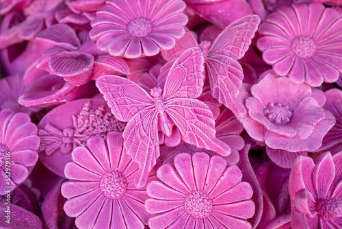 All over pink rose texture made of small soap bars in flower shape. Beautiful background of summer flowers. in the center is a butterfly piece