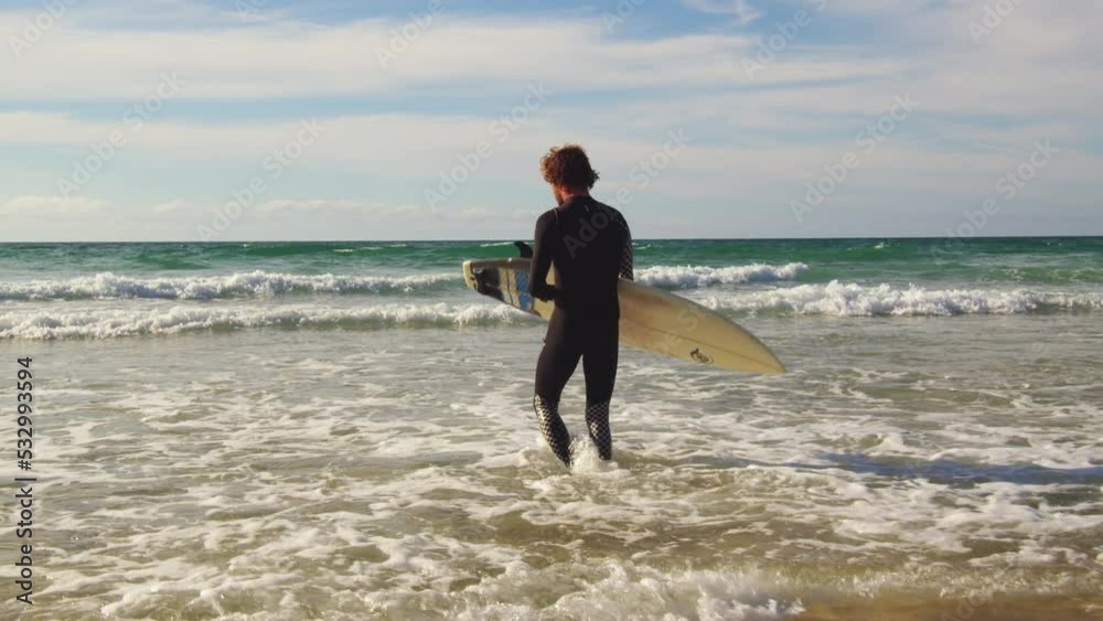 Surf man entering to the ocean with his surfboard Surf man entering to the ocean with his surfboard