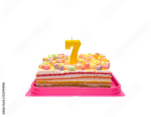 multi-colored rainbow cake in a transparent box with a red bow. Birthday cake with candle number 7 isolated on white background.