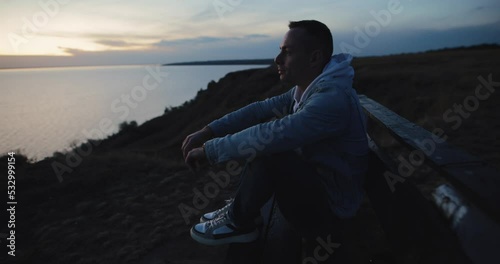 Relaxed man enjoying freedom sitting on a hill above the sea