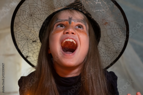 Crazy little witch laughs maliciously at Halloween night photo