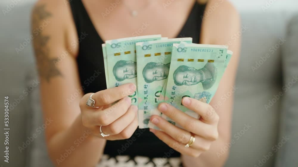 Young woman counting china 50 yuan banknotes at home