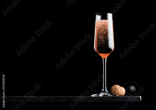 Elegant glass of pink rose champagne with cork and wire cage on black marble board on black background. Space for text