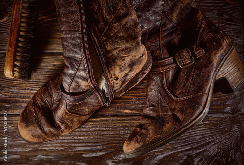 Vintage distressed leather shoes, grunge brown leather boots, rough wooden background 