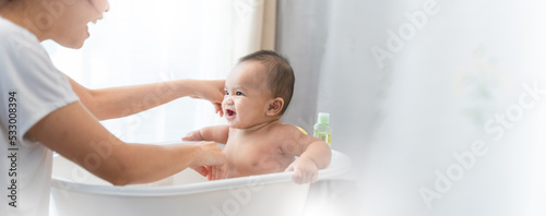 young Asian mother is Bathing with her newborn baby In Bathtub at home.Concept of newborn,baby,parenthood,motherhood,childhood,New life,maternity,love,new family member
