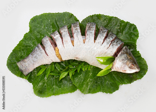 The rohu, rui, or roho labeo is a species of fish of the carp family, found in rivers in South Asia. Fish market display. raw, uncooked, sliced and top view with leaves. photo