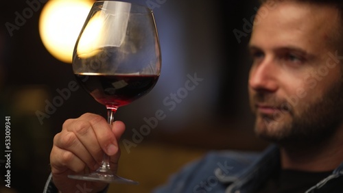 Man sitting in dark room drinking tasting wine.