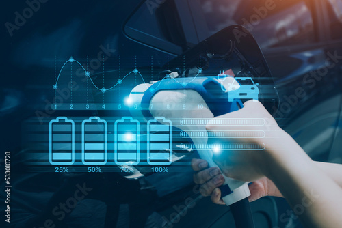 Hand plugging in a charger in an electric car socket.Electric car or ev is charging at station