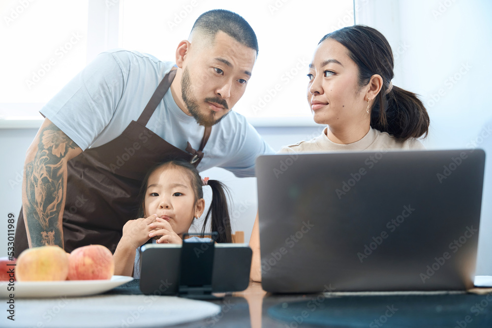 Husband helps his wife with online work, their daughter is nearby