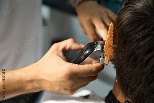 Experienced hair specialist using clipper to cut man hair