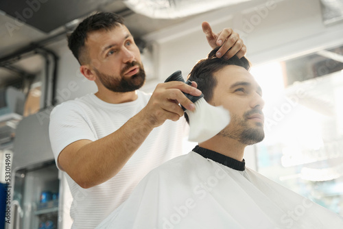 Cheerful guy enjoying top quality service at hair salon