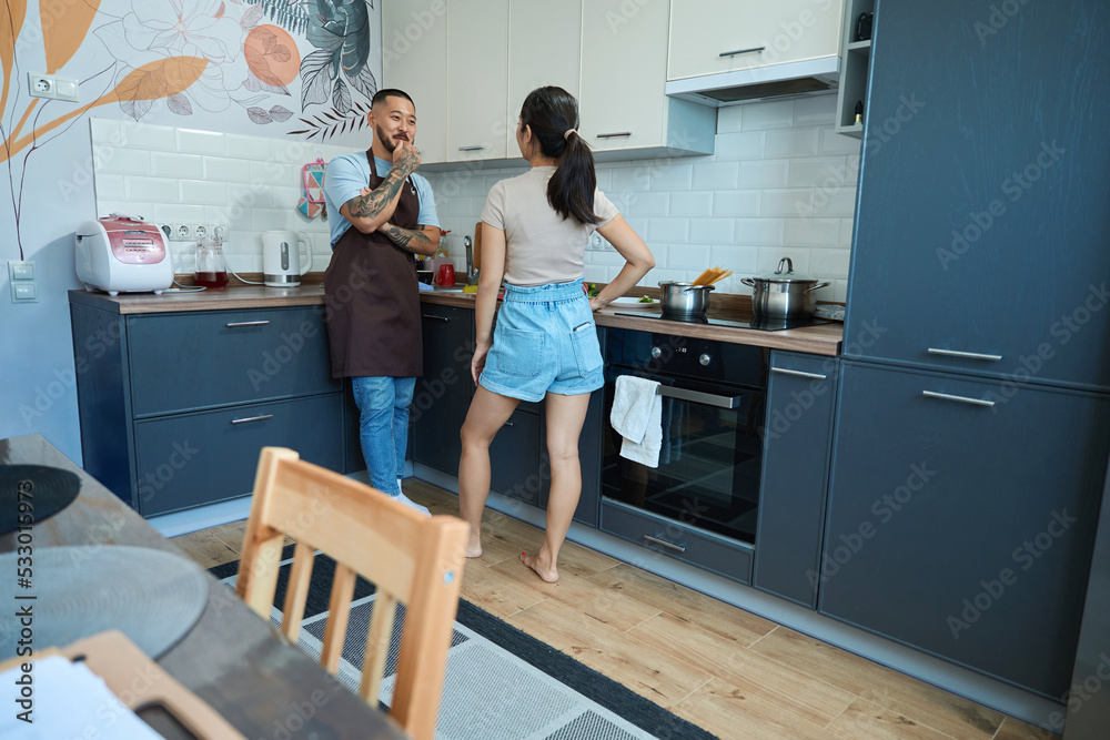 Man and woman are talking cheerfully about something in kitchen Man and woman are talking cheerfully about something in kitchen