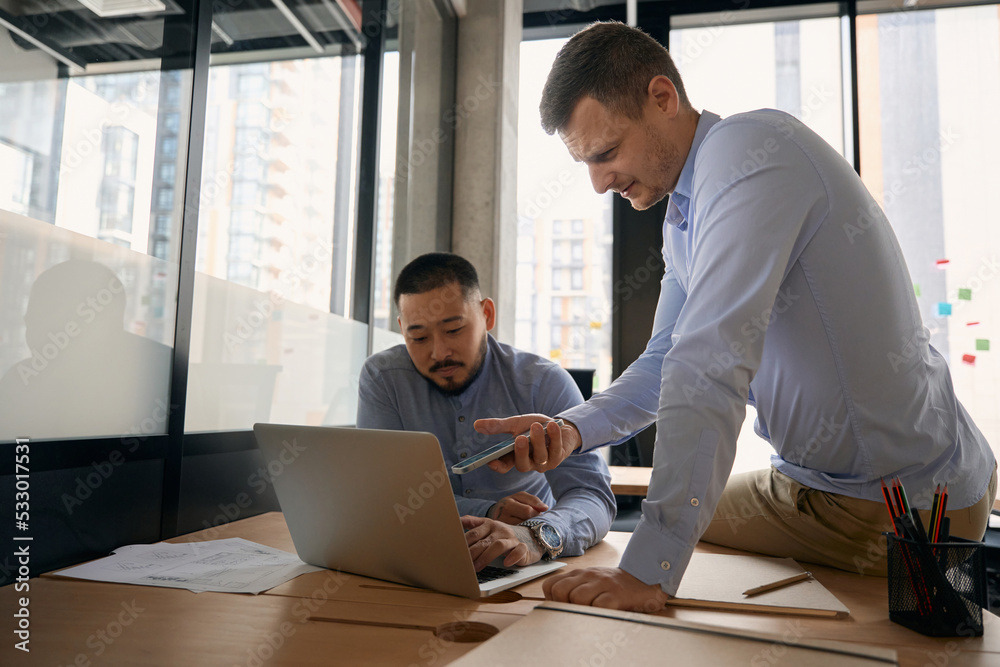 Corporate workers sending files from mobile device to laptop Corporate workers sending files from mobile device to laptop