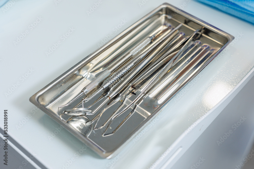 Tray with metal dental tools. Tools of the dentist. Interior of a patient reception room with dental equipment in a dental clinic. Tray with metal dental tools. Tools of the dentist. Interior of a patient reception room with dental equipment in a dental clinic.