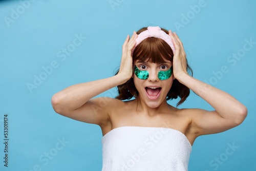 Horizontal photo, a woman with ideal smooth skin on a blue background with luxurious dark hair and bright green luxurious patches. beauty industry
