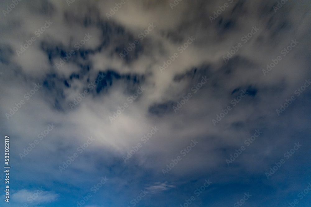 Dark blue sky on long exposure with moving clouds at night