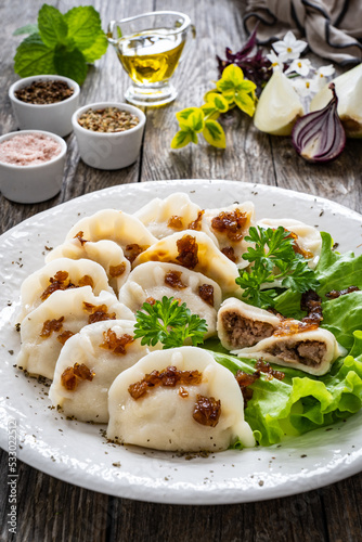 Dumplings - meat dumplings with onion and bacon on wooden table 