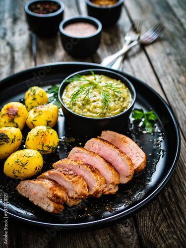 Roast pork loin with fried potatoes and cabbage on wooden table