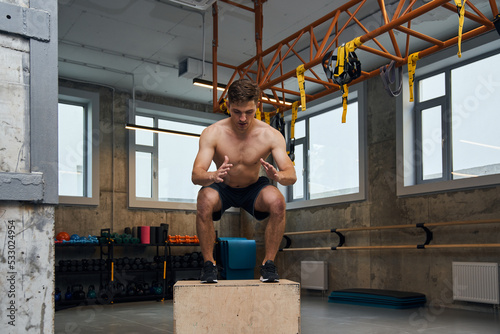 Full length view image of the fit young man doing box jump exercise photo