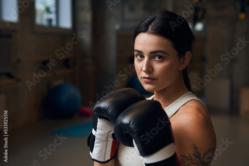 Sportswoman wearing special gloves looking at the camera after boxing workout at gym © Yakobchuk Olena