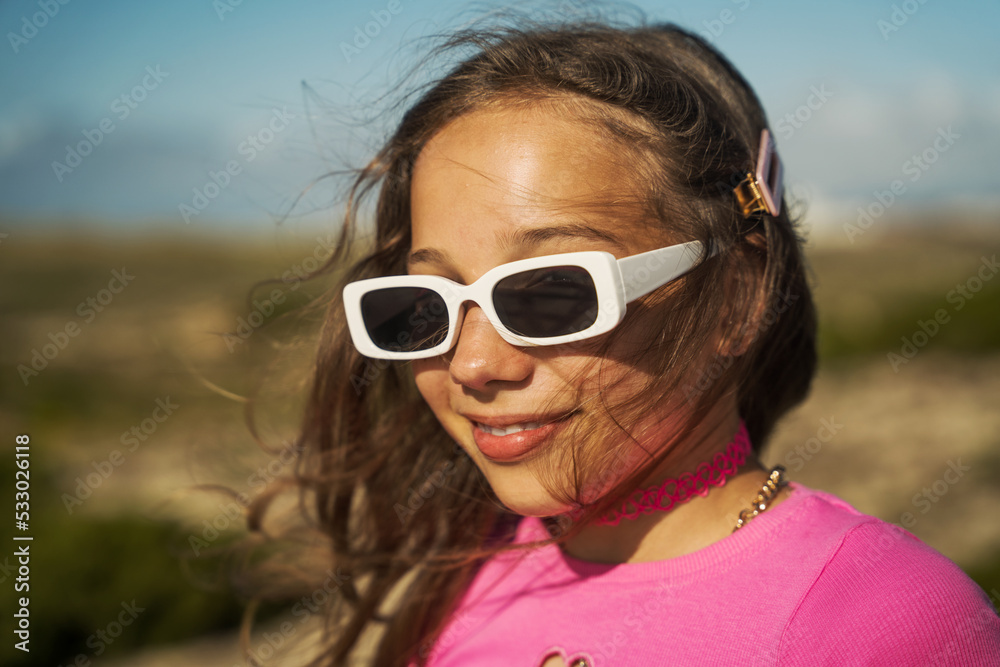 Baby girl in stylish sunglasses smiling while walking at the countryside Baby girl in stylish sunglasses smiling while walking at the countryside