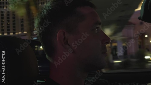 Young man driving a car cabriolet on the main street in Las Vegas at night, close-up. Men in convertible driving through downtown Las Vegas. Man in a car in Las Vegas. Focus on the head of a man.