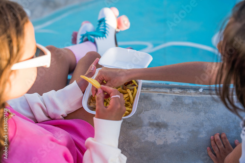 Little girls eating fast food with appetite and spending time with each other at the rollerdrome photo