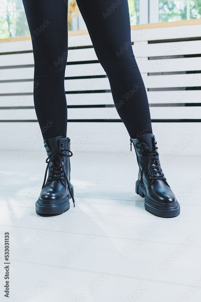 Female legs in black leather boots close-up. Autumn women's boots without a heel Female legs in black leather boots close-up. Autumn women's boots without a heel