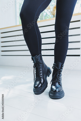 Female legs in black leather boots close-up. Autumn women's boots without a heel