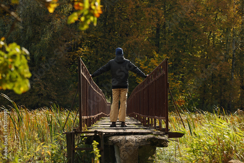 Young man in a black jacket standing on a narrow bridge. Pavel, i on narrow bridge and autumn nature around me. Photo was taken 20 September 2022 year, MSK time in Russia.