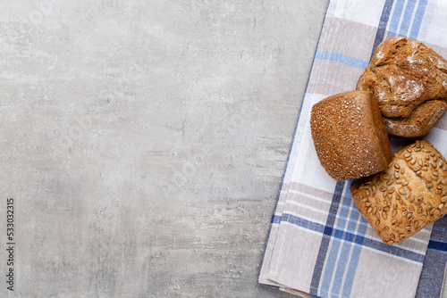 Gold rustic crusty loaves of bread and buns on wooden background. Still life captured from above top view, flat lay.