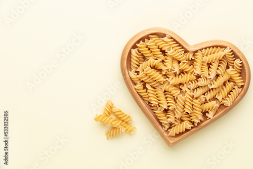 Pasta in a heart shaped wood bowl.