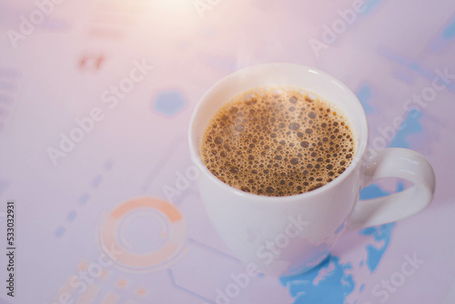 A cup of bubbly coffee is placed on a businessman's desk surrounded by paper charts.