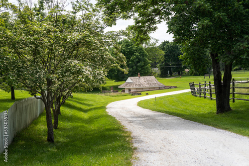 Fototapeta Naklejka Na Ścianę i Meble -  The dairy at Hampton National Historic Site in Towson, Maryland. The farm side of the park shows low dairy building built over a spring to keep milk cold. Winding path, flowering trees and fences. 