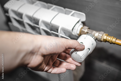 Hand regulating the radiator temperature with a thermostatic head, selective focus photo