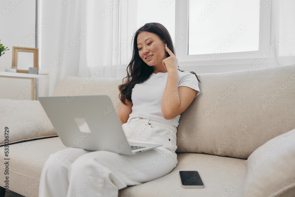 Asian woman sits with laptop and phone in home freelancer's hangout with staring at laptop screen working, lifestyle work and home Asian woman sits with laptop and phone in home freelancer's hangout with staring at laptop screen working, lifestyle work and home