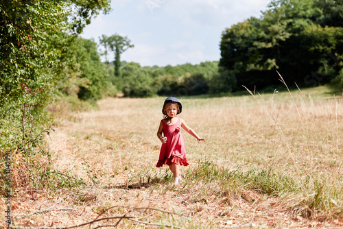 petite fille coure dans un champs en été