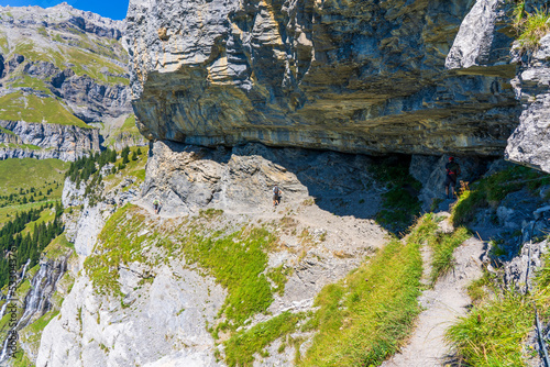 People walking on the edge of cliff in Swiss Alps in canton of Bern during the sunny day