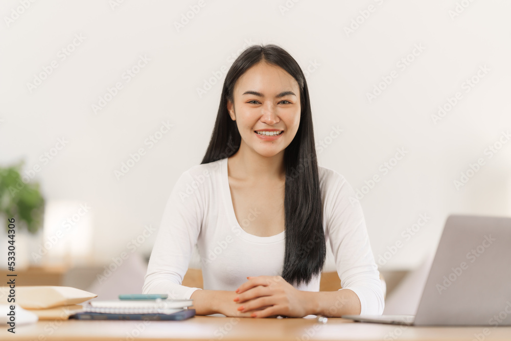 Confident smiling asian woman in creative home office looking at camera. Confident smiling asian woman in creative home office looking at camera.