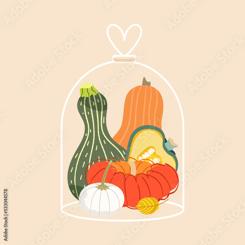 Pumpkins in glass cloche jar. Autumn vegetables hygge mood. Cozy fall thanksgiving Halloween decoration objects isolated on beige background. Home decor
