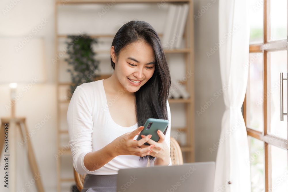 Portrait of smile asian woman freelancer using mobile phone at home office.