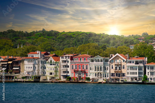 View from the sea of the green mountains of the asian side of Bosphorus strait, with traditional houses and dense trees in a summer day before sunset