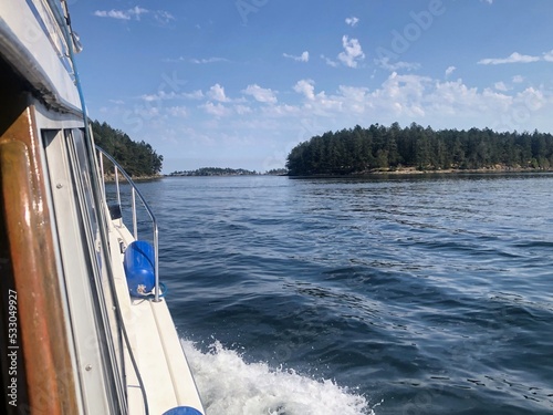 Action view of a boat sailing across the ocean towards an island on a beautiful summer day in the gulf islands, british columbia, canada © christopher