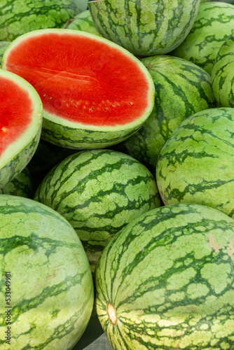 A large pile of watermelons on a market stall.