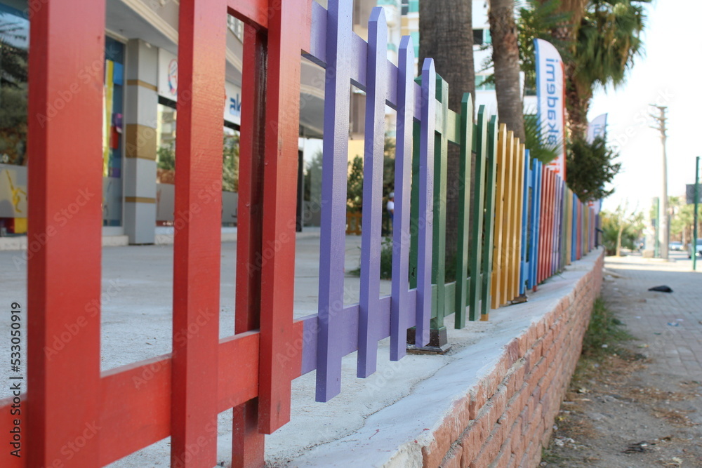 Rainbow colored fences on a tiny brick wall
