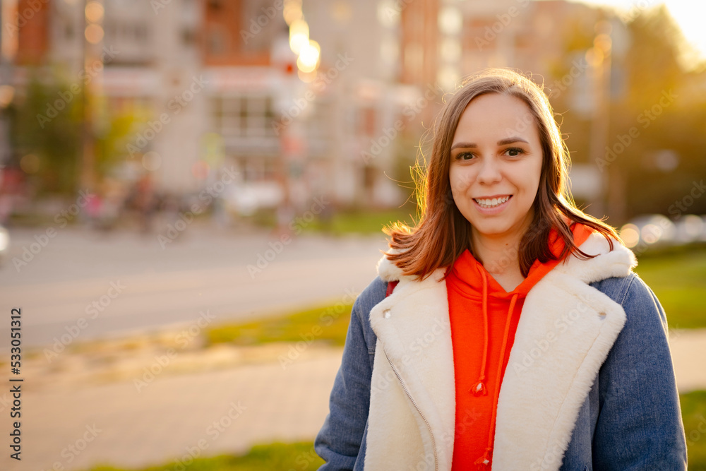 Portrait of positive young woman looking at camera, smiling, standing on city street at sunset. Portrait of positive young woman looking at camera, smiling, standing on city street at sunset.
