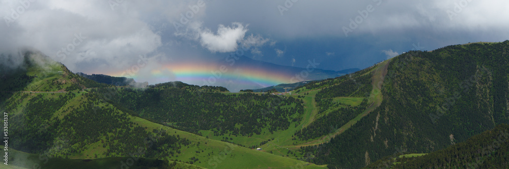 Mountain Landcape in Andorra during spring season ; bright beautiful rainbow in a valley