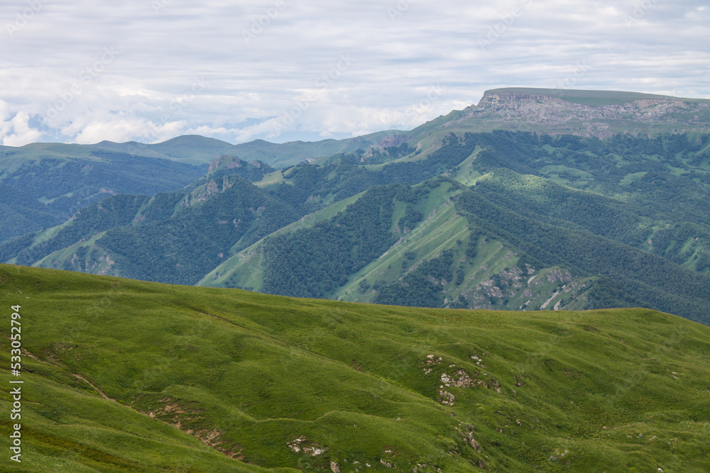 Fantastic dramatic landscape - panoramic view of the hilly valley blurred in the morning fog from the Bermamyt plateau in Karachay Cherkessia on a cloudy summer day and space for copying