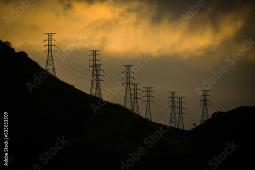 Silhouette of electrical pylons at sunset on the hills above the Zona Norte, or North Zone of Rio de Janeiro, Brazil